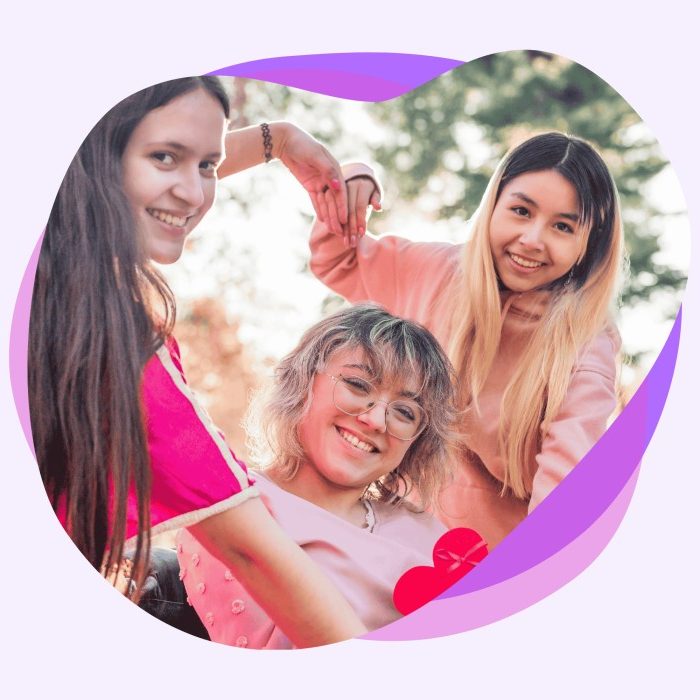 Two friends holding hands forming a love heart around their friend in a wheelchair