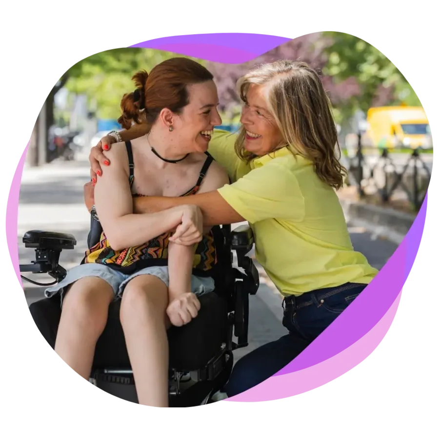 Female support worker embracing a female participant in a wheelchair